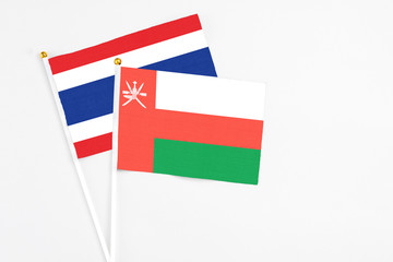 Oman and Thailand stick flags on white background. High quality fabric, miniature national flag. Peaceful global concept.White floor for copy space.