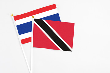 Trinidad And Tobago and Thailand stick flags on white background. High quality fabric, miniature national flag. Peaceful global concept.White floor for copy space.