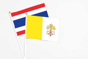 Fototapeta premium Vatican City and Thailand stick flags on white background. High quality fabric, miniature national flag. Peaceful global concept.White floor for copy space.