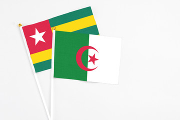 Algeria and Togo stick flags on white background. High quality fabric, miniature national flag. Peaceful global concept.White floor for copy space.