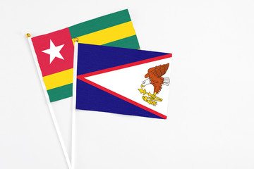 American Samoa and Togo stick flags on white background. High quality fabric, miniature national flag. Peaceful global concept.White floor for copy space.