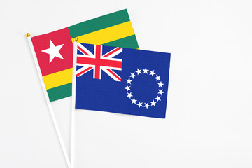 Fototapeta premium Cook Islands and Togo stick flags on white background. High quality fabric, miniature national flag. Peaceful global concept.White floor for copy space.