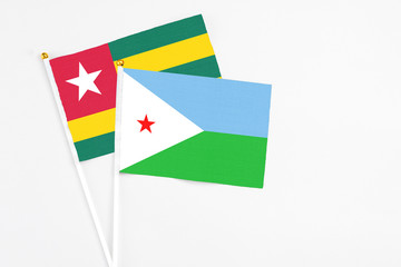 Djibouti and Togo stick flags on white background. High quality fabric, miniature national flag. Peaceful global concept.White floor for copy space.