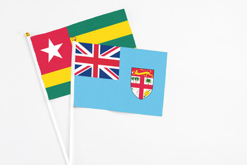 Fototapeta premium Fiji and Togo stick flags on white background. High quality fabric, miniature national flag. Peaceful global concept.White floor for copy space.