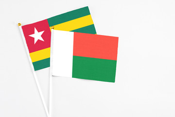 Madagascar and Togo stick flags on white background. High quality fabric, miniature national flag. Peaceful global concept.White floor for copy space.