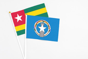 Northern Mariana Islands and Togo stick flags on white background. High quality fabric, miniature national flag. Peaceful global concept.White floor for copy space.
