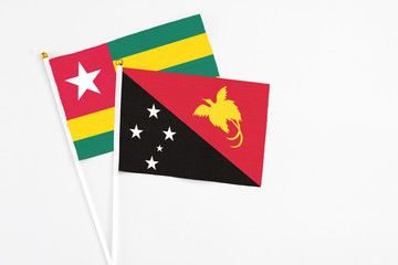 Papua New Guinea and Togo stick flags on white background. High quality fabric, miniature national flag. Peaceful global concept.White floor for copy space.