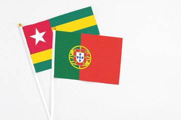 Portugal and Togo stick flags on white background. High quality fabric, miniature national flag. Peaceful global concept.White floor for copy space.