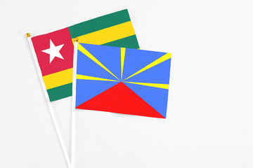 Reunion and Togo stick flags on white background. High quality fabric, miniature national flag. Peaceful global concept.White floor for copy space.