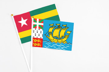Saint Pierre And Miquelon and Togo stick flags on white background. High quality fabric, miniature national flag. Peaceful global concept.White floor for copy space.
