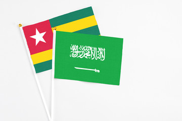 Saudi Arabia and Togo stick flags on white background. High quality fabric, miniature national flag. Peaceful global concept.White floor for copy space.