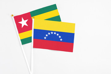 Venezuela and Togo stick flags on white background. High quality fabric, miniature national flag. Peaceful global concept.White floor for copy space.