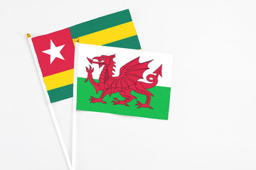 Wales and Togo stick flags on white background. High quality fabric, miniature national flag. Peaceful global concept.White floor for copy space.