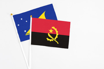 Angola and Tokelau stick flags on white background. High quality fabric, miniature national flag. Peaceful global concept.White floor for copy space.