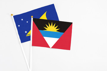 Antigua and Barbuda and Tokelau stick flags on white background. High quality fabric, miniature national flag. Peaceful global concept.White floor for copy space.