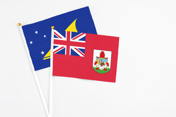 Fototapeta premium Bermuda and Tokelau stick flags on white background. High quality fabric, miniature national flag. Peaceful global concept.White floor for copy space.