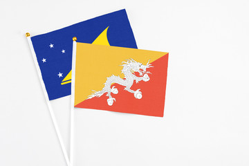 Bhutan and Tokelau stick flags on white background. High quality fabric, miniature national flag. Peaceful global concept.White floor for copy space.