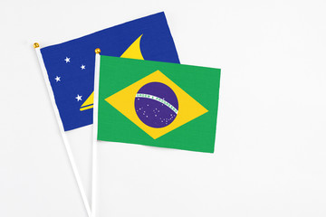 Brazil and Tokelau stick flags on white background. High quality fabric, miniature national flag. Peaceful global concept.White floor for copy space.