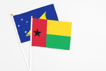 Guinea Bissau and Tokelau stick flags on white background. High quality fabric, miniature national flag. Peaceful global concept.White floor for copy space.