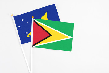 Guyana and Tokelau stick flags on white background. High quality fabric, miniature national flag. Peaceful global concept.White floor for copy space.