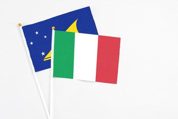 Italy and Tokelau stick flags on white background. High quality fabric, miniature national flag. Peaceful global concept.White floor for copy space.