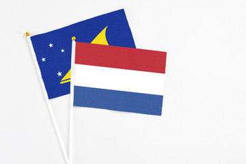 Netherlands and Tokelau stick flags on white background. High quality fabric, miniature national flag. Peaceful global concept.White floor for copy space.