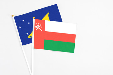 Oman and Tokelau stick flags on white background. High quality fabric, miniature national flag. Peaceful global concept.White floor for copy space.