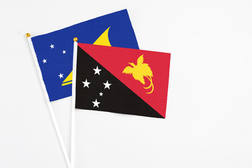 Papua New Guinea and Tokelau stick flags on white background. High quality fabric, miniature national flag. Peaceful global concept.White floor for copy space.