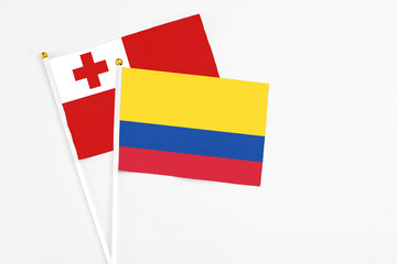 Colombia and Tonga stick flags on white background. High quality fabric, miniature national flag. Peaceful global concept.White floor for copy space.