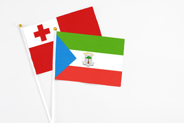 Equatorial Guinea and Tonga stick flags on white background. High quality fabric, miniature national flag. Peaceful global concept.White floor for copy space.