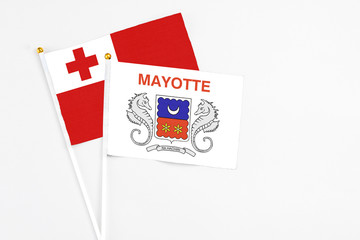 Mayotte and Tonga stick flags on white background. High quality fabric, miniature national flag. Peaceful global concept.White floor for copy space.