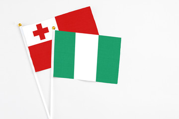 Fototapeta premium Nigeria and Tonga stick flags on white background. High quality fabric, miniature national flag. Peaceful global concept.White floor for copy space.