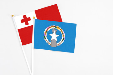 Northern Mariana Islands and Tonga stick flags on white background. High quality fabric, miniature national flag. Peaceful global concept.White floor for copy space.