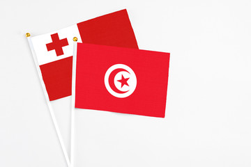 Tunisia and Tonga stick flags on white background. High quality fabric, miniature national flag. Peaceful global concept.White floor for copy space.