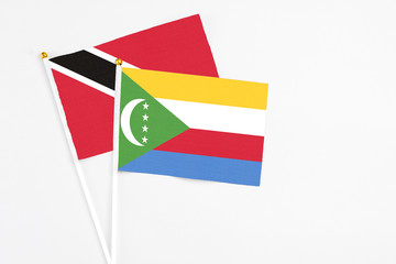 Comoros and Trinidad And Tobago stick flags on white background. High quality fabric, miniature national flag. Peaceful global concept.White floor for copy space.