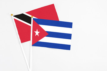 Cuba and Trinidad And Tobago stick flags on white background. High quality fabric, miniature national flag. Peaceful global concept.White floor for copy space.