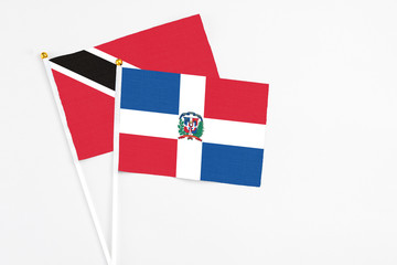 Dominican Republic and Trinidad And Tobago stick flags on white background. High quality fabric, miniature national flag. Peaceful global concept.White floor for copy space.