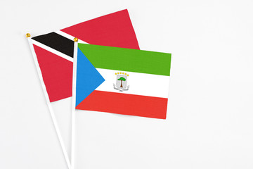 Equatorial Guinea and Trinidad And Tobago stick flags on white background. High quality fabric, miniature national flag. Peaceful global concept.White floor for copy space.