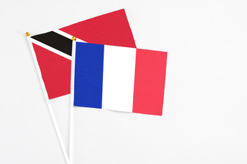 France and Trinidad And Tobago stick flags on white background. High quality fabric, miniature national flag. Peaceful global concept.White floor for copy space.