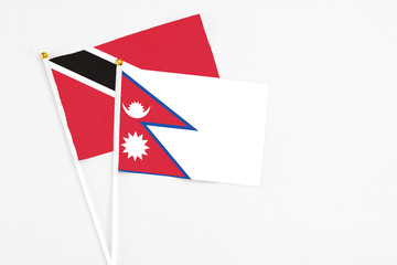 Nepal and Trinidad And Tobago stick flags on white background. High quality fabric, miniature national flag. Peaceful global concept.White floor for copy space.