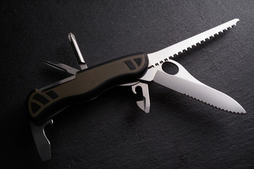 Multipurpose survivor tool knife on dark slate stone background