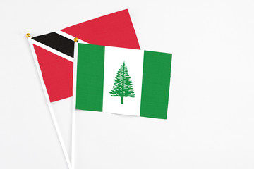 Norfolk Island and Trinidad And Tobago stick flags on white background. High quality fabric, miniature national flag. Peaceful global concept.White floor for copy space.