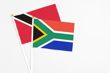 South Africa and Trinidad And Tobago stick flags on white background. High quality fabric, miniature national flag. Peaceful global concept.White floor for copy space.