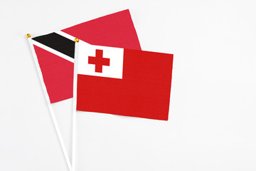 Tonga and Trinidad And Tobago stick flags on white background. High quality fabric, miniature national flag. Peaceful global concept.White floor for copy space.