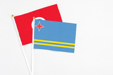 Aruba and Tunisia stick flags on white background. High quality fabric, miniature national flag. Peaceful global concept.White floor for copy space.