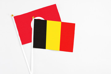 Belgium and Tunisia stick flags on white background. High quality fabric, miniature national flag. Peaceful global concept.White floor for copy space.