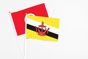 Brunei and Tunisia stick flags on white background. High quality fabric, miniature national flag. Peaceful global concept.White floor for copy space.