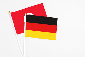 Germany and Tunisia stick flags on white background. High quality fabric, miniature national flag. Peaceful global concept.White floor for copy space.