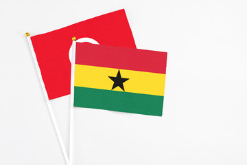 Ghana and Tunisia stick flags on white background. High quality fabric, miniature national flag. Peaceful global concept.White floor for copy space.