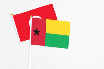 Guinea Bissau and Tunisia stick flags on white background. High quality fabric, miniature national flag. Peaceful global concept.White floor for copy space.